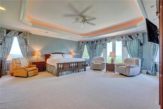 carpeted bedroom with ceiling fan, a raised ceiling, and crown molding