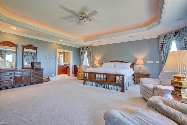 bedroom featuring ceiling fan, a tray ceiling, light carpet, and ensuite bathroom