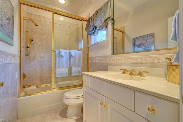 full bathroom with tile walls, vanity, crown molding, combined bath / shower with glass door, and toilet