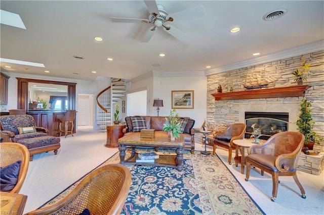 living room featuring carpet flooring, a skylight, a stone fireplace, ornamental molding, and ceiling fan