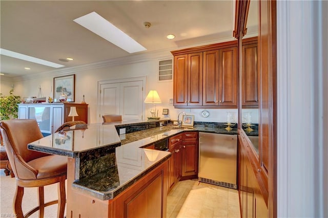 kitchen featuring kitchen peninsula, dishwasher, dark stone counters, crown molding, and a kitchen bar