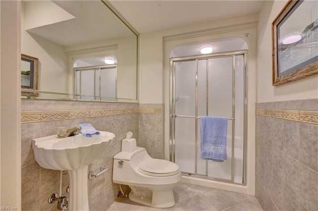 bathroom featuring tile walls, toilet, and an enclosed shower