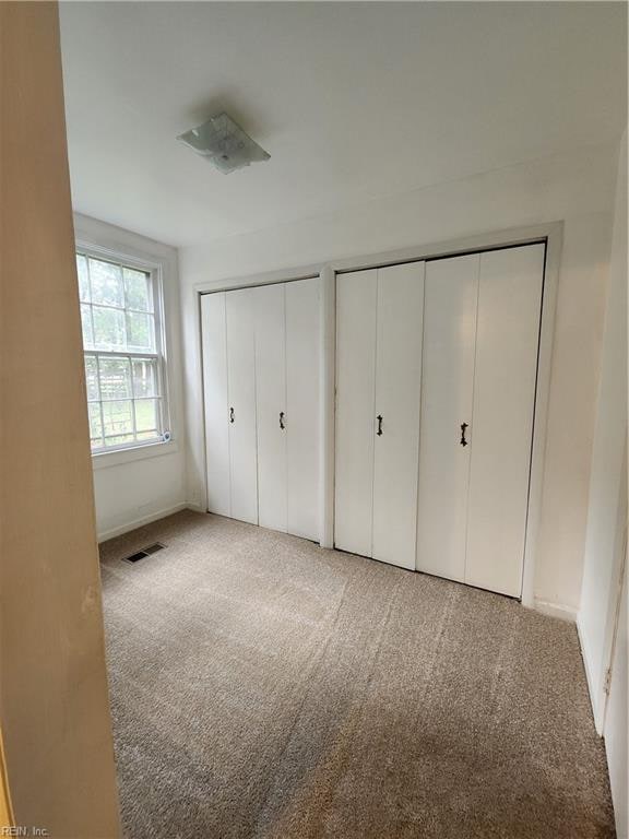 unfurnished bedroom featuring multiple closets and light colored carpet