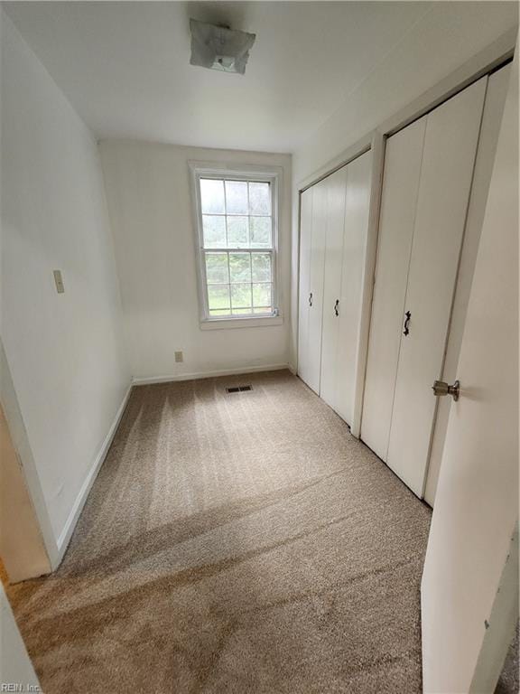 unfurnished bedroom with multiple closets and light colored carpet