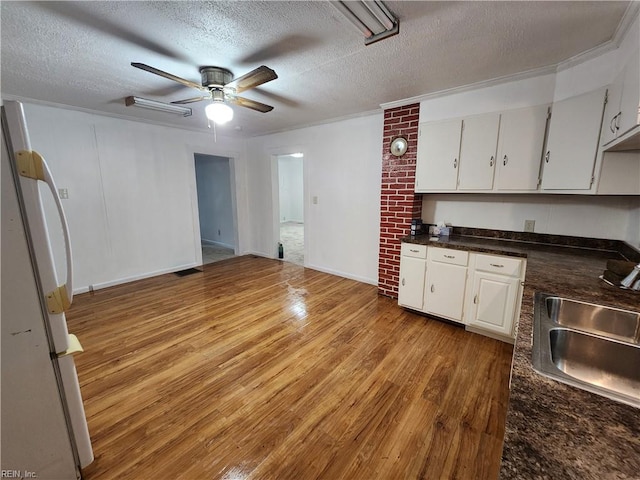 kitchen featuring light hardwood / wood-style floors, a textured ceiling, sink, white cabinets, and ceiling fan