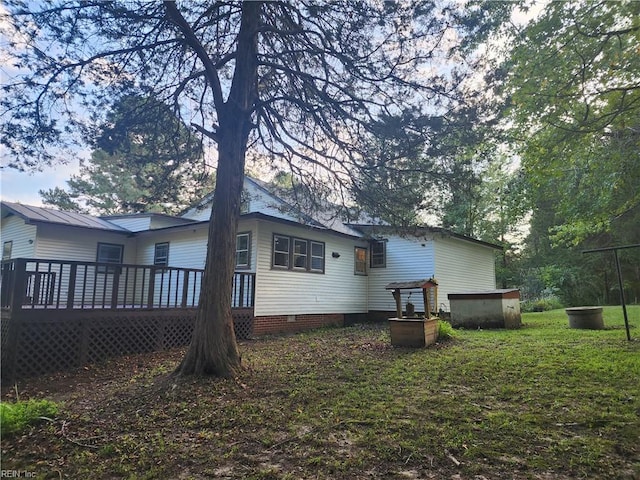 back of property with a deck and a lawn