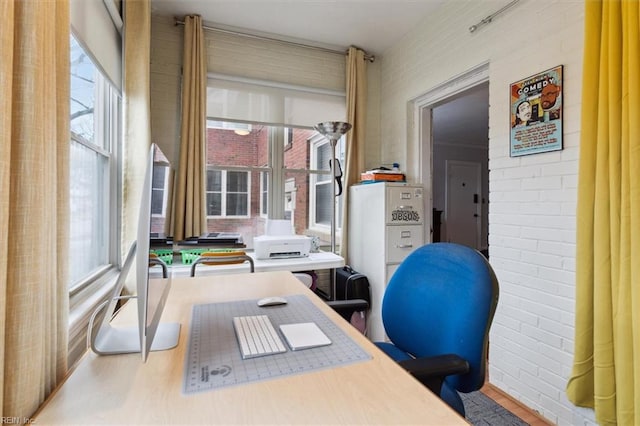 office area with brick wall and hardwood / wood-style floors