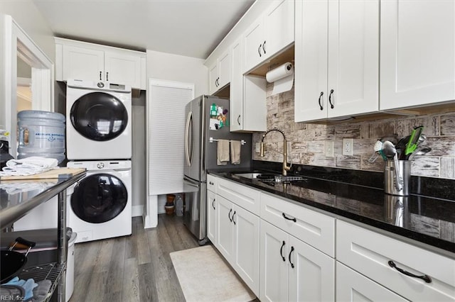 interior space featuring sink, white cabinetry, dark stone counters, stacked washer and dryer, and dark hardwood / wood-style flooring