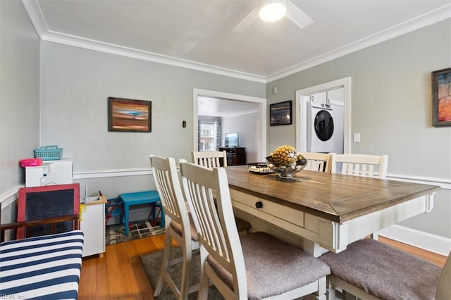 dining area featuring light hardwood / wood-style flooring, ceiling fan, crown molding, and stacked washing maching and dryer