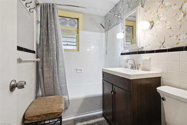 full bathroom with vanity, tile walls, shower / bath combo with shower curtain, and toilet