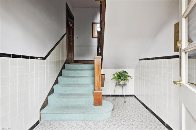 stairs with tile walls and vaulted ceiling