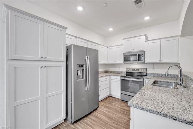 kitchen with stainless steel appliances, white cabinets, light hardwood / wood-style floors, and sink