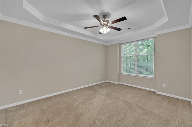 empty room with ornamental molding, light colored carpet, ceiling fan, and a raised ceiling