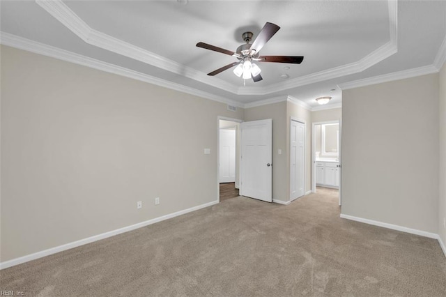 unfurnished bedroom featuring ceiling fan, a tray ceiling, light carpet, and ornamental molding