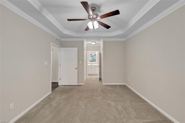 empty room featuring ceiling fan, a tray ceiling, light carpet, and ornamental molding