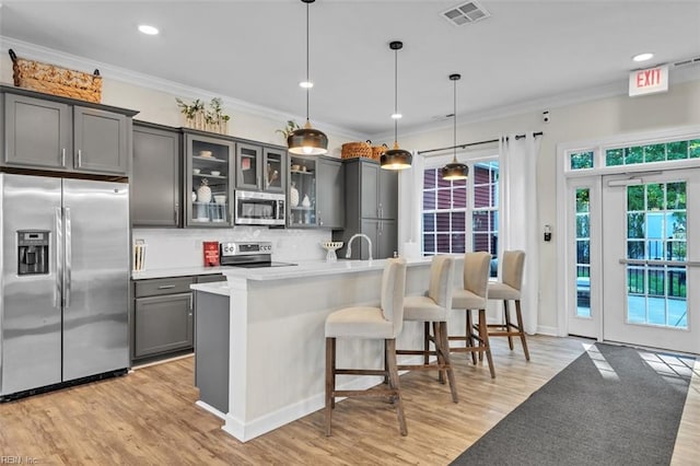 kitchen featuring appliances with stainless steel finishes, light hardwood / wood-style flooring, pendant lighting, and plenty of natural light