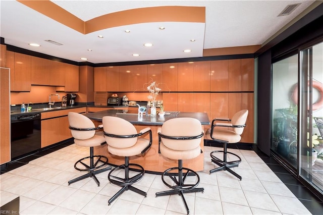 kitchen featuring black dishwasher, a kitchen island, light tile patterned flooring, and a breakfast bar area