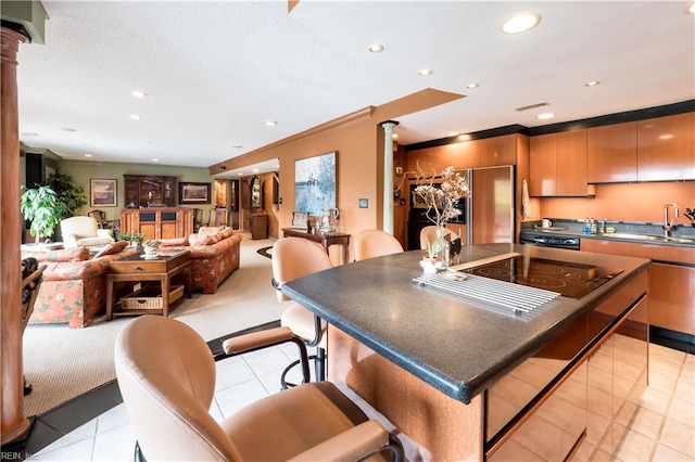 kitchen with a breakfast bar area, light tile patterned floors, stainless steel appliances, crown molding, and sink