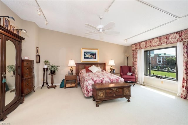 carpeted bedroom with ceiling fan and track lighting