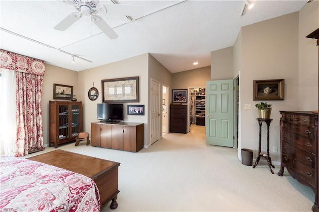 bedroom with rail lighting, a closet, lofted ceiling, ceiling fan, and light colored carpet