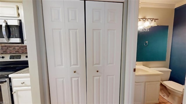 interior space with ornamental molding, vanity, tile patterned floors, and toilet