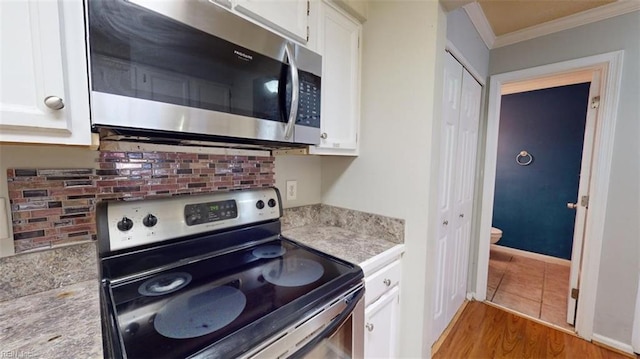 kitchen featuring stainless steel appliances, white cabinets, light hardwood / wood-style floors, and crown molding