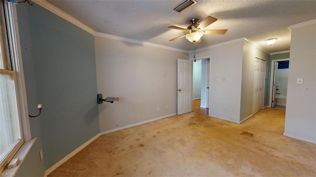 carpeted spare room with a textured ceiling, ornamental molding, and ceiling fan