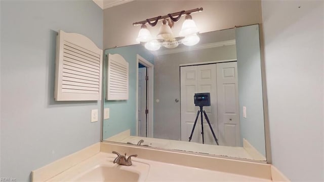 bathroom featuring an inviting chandelier, ornamental molding, and sink