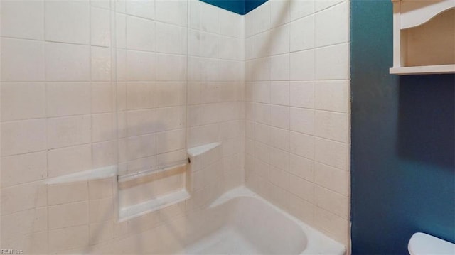 bathroom with tiled shower / bath combo and toilet