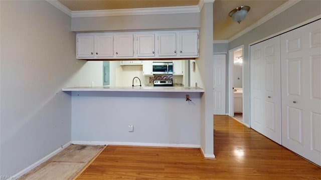 kitchen with crown molding, light hardwood / wood-style floors, stainless steel appliances, and white cabinets