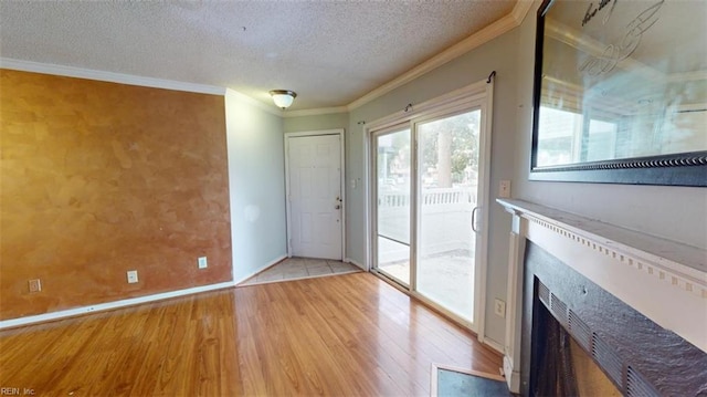 entryway with a textured ceiling, light hardwood / wood-style floors, and ornamental molding