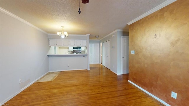 unfurnished living room with a notable chandelier, a textured ceiling, crown molding, and hardwood / wood-style floors