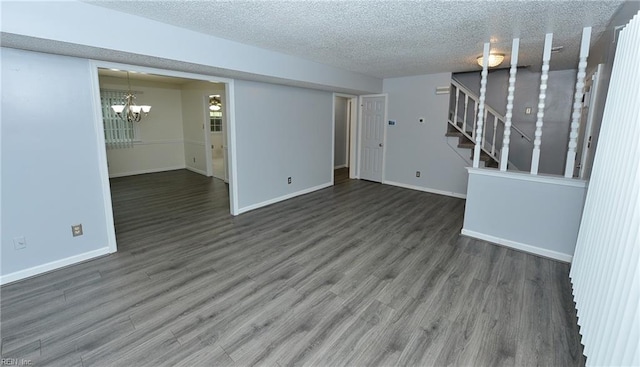 spare room featuring a notable chandelier, dark wood-type flooring, and a textured ceiling