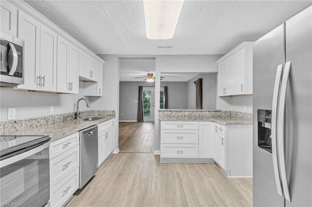 kitchen with white cabinets, stainless steel appliances, and light hardwood / wood-style floors