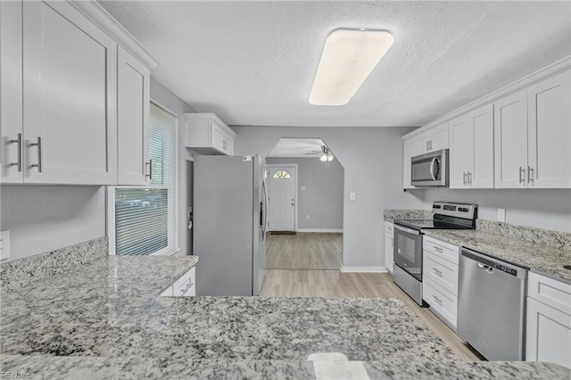 kitchen featuring appliances with stainless steel finishes, ceiling fan, light hardwood / wood-style flooring, and white cabinets