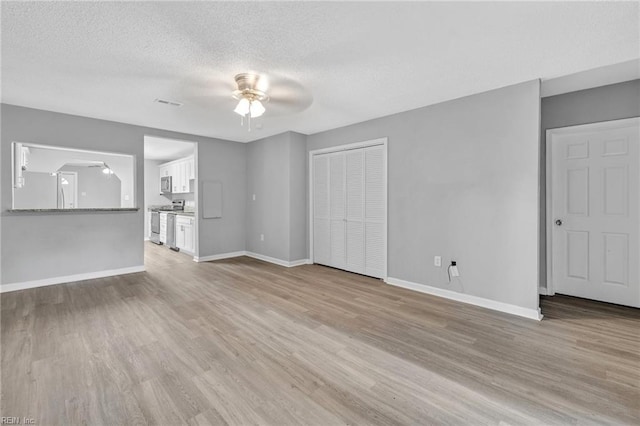 unfurnished living room featuring a textured ceiling, light hardwood / wood-style floors, and ceiling fan