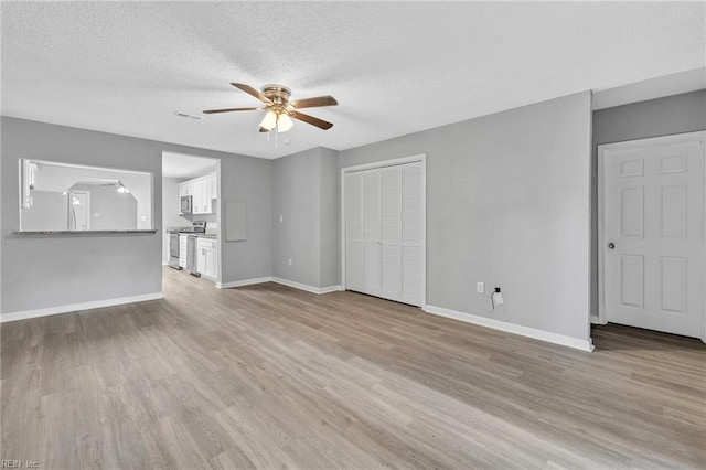 unfurnished living room with light hardwood / wood-style floors, ceiling fan, and a textured ceiling