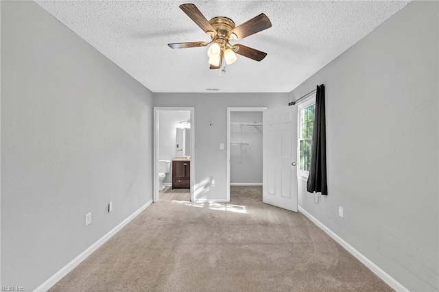 unfurnished bedroom featuring ceiling fan, a textured ceiling, a closet, light carpet, and ensuite bathroom