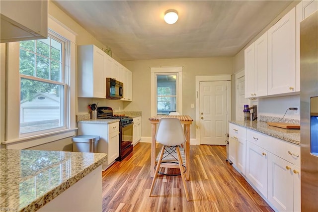 kitchen featuring light hardwood / wood-style flooring, white cabinets, light stone countertops, and black range with gas cooktop