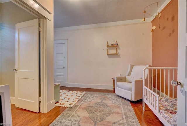 interior space featuring wood-type flooring, crown molding, and a crib