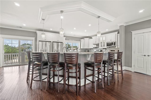 kitchen with appliances with stainless steel finishes, a wealth of natural light, pendant lighting, and white cabinets