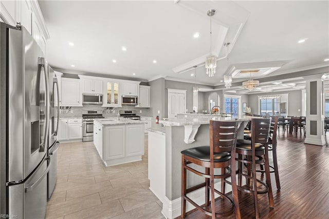 kitchen featuring hanging light fixtures, a large island, white cabinetry, stainless steel appliances, and light hardwood / wood-style floors