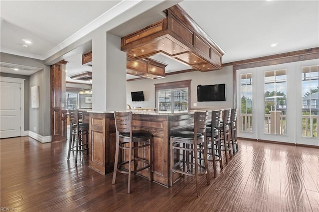 bar with dark wood-type flooring and crown molding