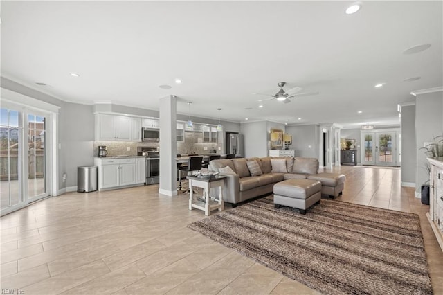 tiled living room featuring decorative columns, ceiling fan, french doors, and crown molding