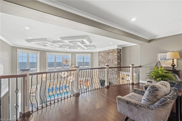 living area with a water view, a raised ceiling, hardwood / wood-style floors, and crown molding