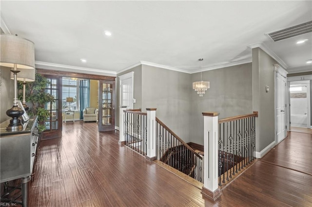 hallway with an inviting chandelier, dark hardwood / wood-style floors, french doors, and crown molding