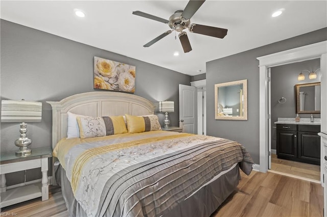 bedroom featuring light wood-type flooring, ceiling fan, and ensuite bathroom