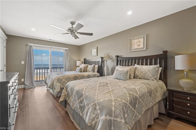 bedroom featuring wood-type flooring, a water view, ceiling fan, and access to outside