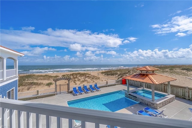 view of swimming pool with a beach view, a water view, an in ground hot tub, and a patio area