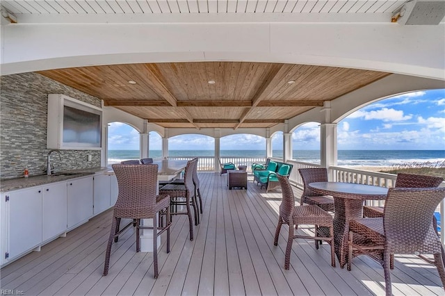 deck featuring a view of the beach, a water view, and sink